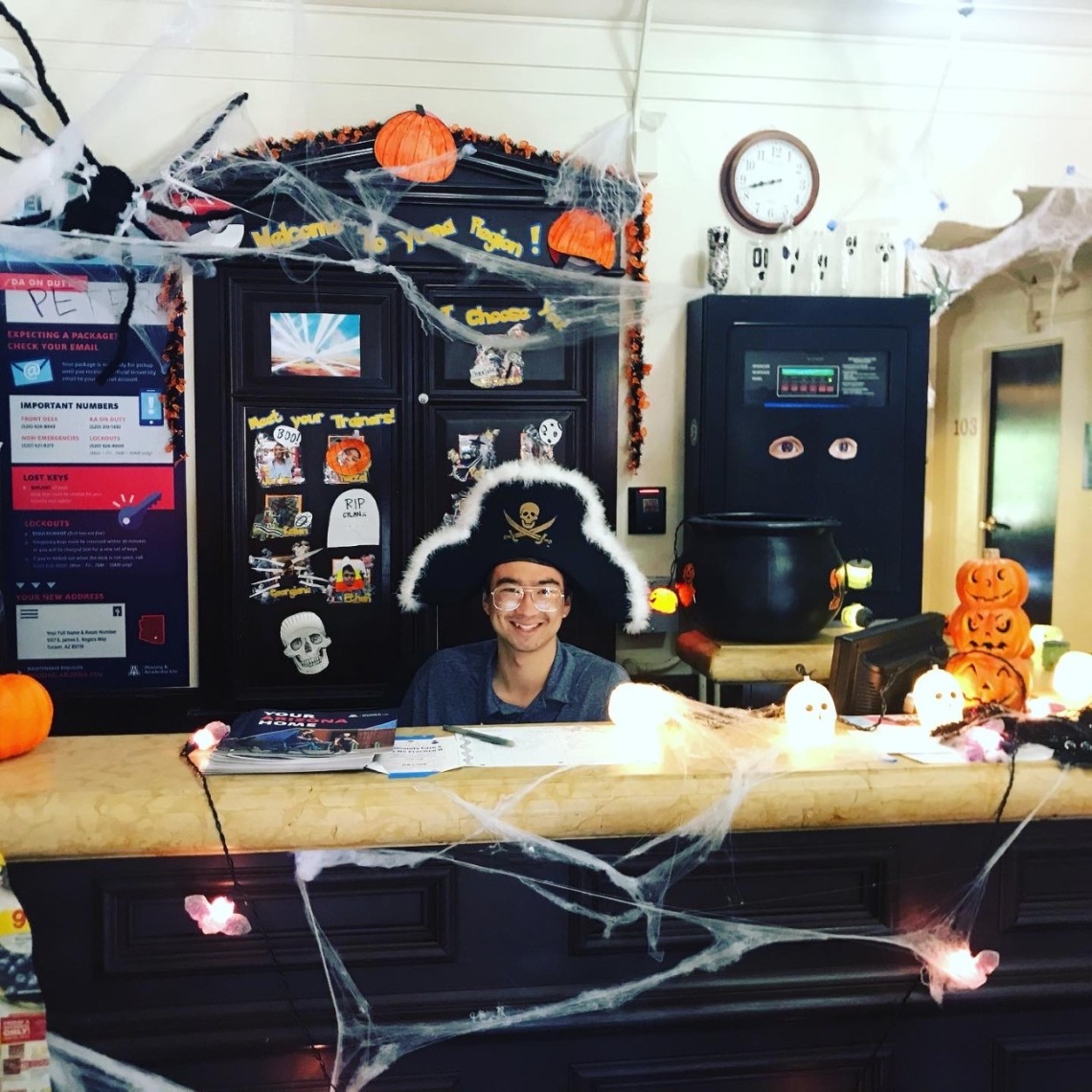 Desk Assistant dressed as pirate on Halloween behind dorm front desk.